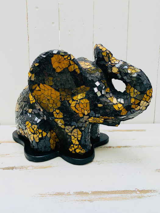 Side view of mosaic elephant lamp switched off on white background, showing gold and black glass mosaic surface.
