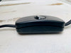 Close-up of black inline switch and cable with UK plug on white wooden background for handmade mosaic lamp.