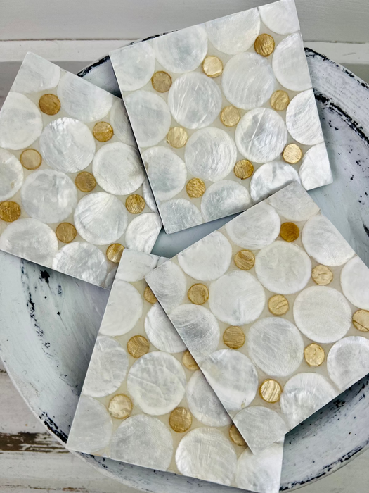 Close-up set of white and cream shell coasters showing natural shell texture and glossy resin coating.
