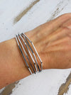 A silver bracelet with a geometric wave design, displayed on a person's wrist.