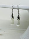 Pair of silver earrings with teardrop-shaped white stones on a white background