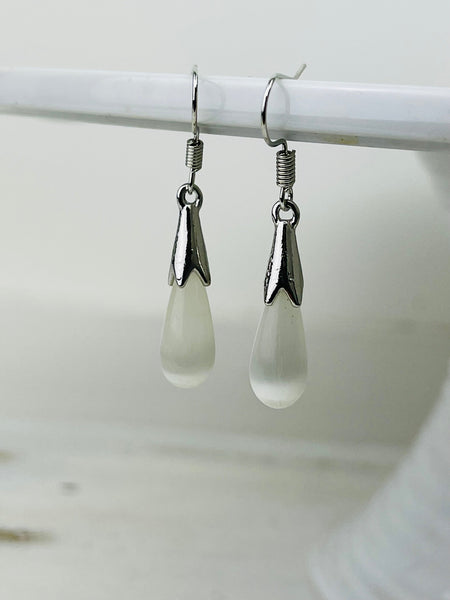 Pair of silver earrings with teardrop-shaped white stones on a white background