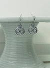 A pair of silver-colored earrings with a simple cross diamond pattern and tiny crystal detail, displayed on a white background.