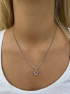 A person wearing a white v-neck t-shirt showcasing a silver necklace with a star pendant.