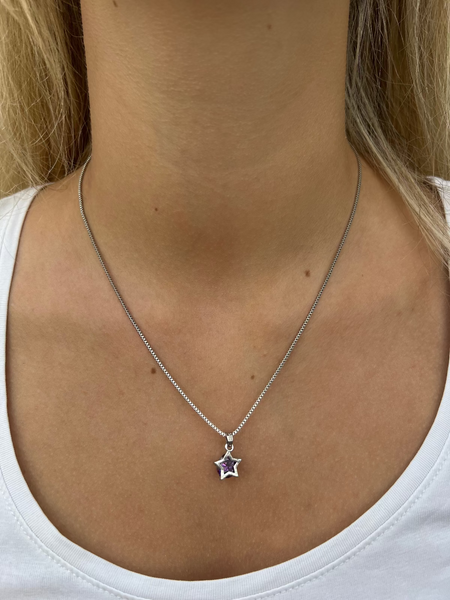 A person wearing a white v-neck t-shirt showcasing a silver necklace with a star pendant.