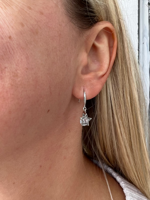 Close-up of a person wearing a silver star-shaped earring.
