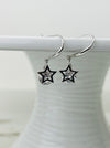 A pair of silver drop earrings with star-shaped cages containing crystal details, displayed against a white background.