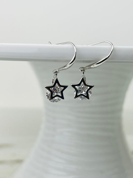 A pair of silver drop earrings with star-shaped cages containing crystal details, displayed against a white background.