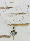 A long chain necklace with a crystal studded ballerina pendant, displayed against a white and blue wooden background.
